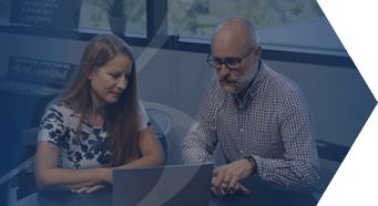 Professional woman and man work together looking at a laptop in an office to compare and select new software solutions