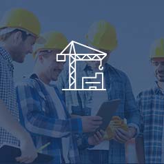 Four men standing in hard hats and flannel shirts looking at a tablet working with ERP software at a construction site